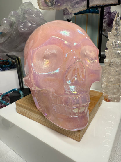 Large Pink Aura Rose Quartz crystal skull, measuring approximately 5 x 5.5 inches and weighing 4 lbs. Features soft pink coloration and a glowing, iridescent surface. Displayed as a carved decorative stone with heart-focused elegance.