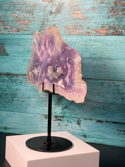 Pink, purple, and blue Fluorite crystal slab on a modern black stand, used as elegant home decor