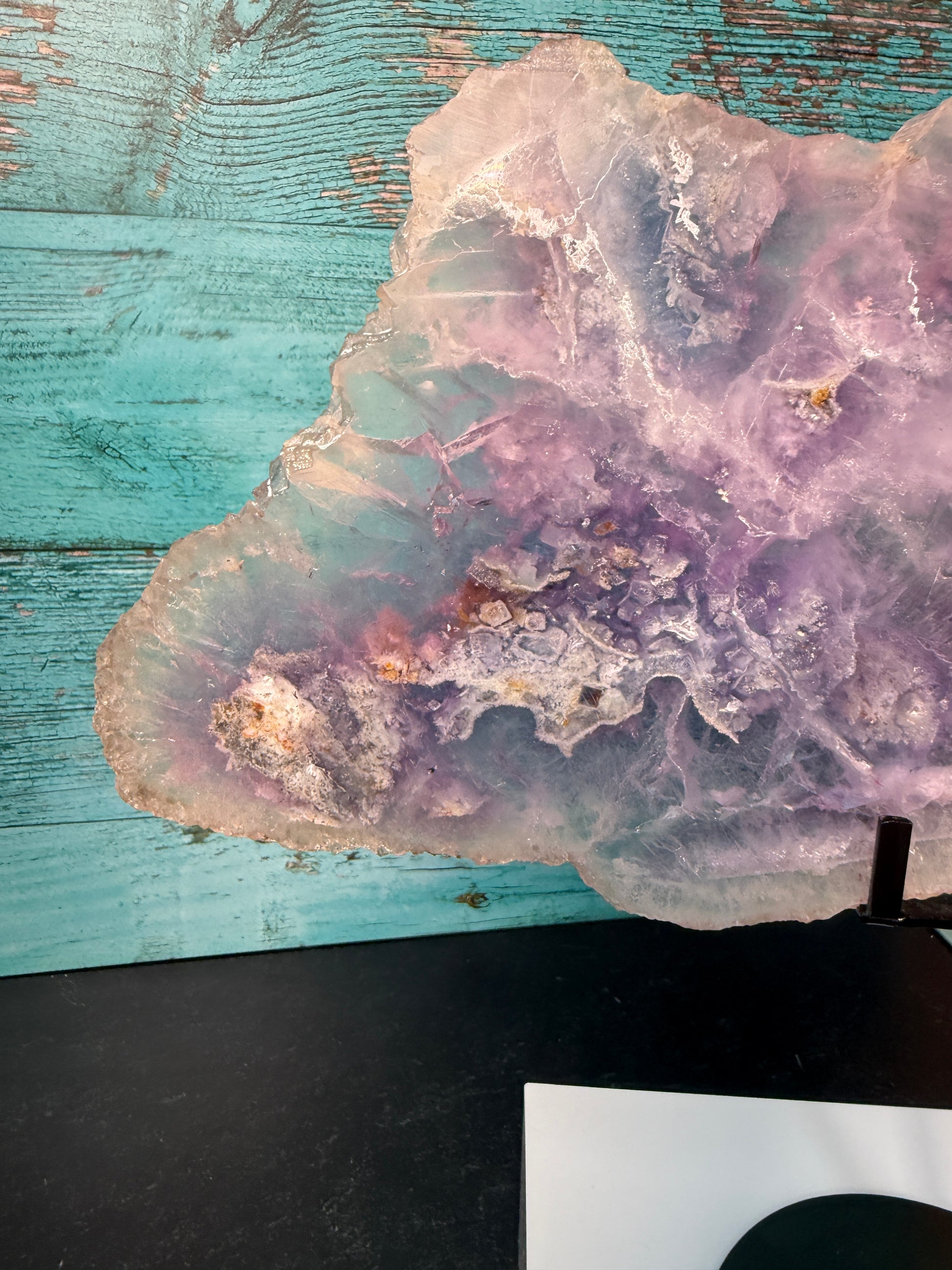 Pink, purple, and blue Fluorite crystal slab on a modern black stand, used as elegant home decor
