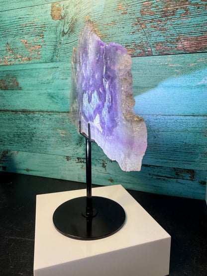 Pink, purple, and blue Fluorite crystal slab on a modern black stand, used as elegant home decor